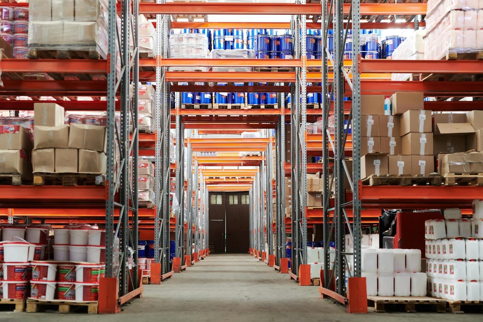 A cold-storage warehouse interior with orange racking and goods stacked in aisles.